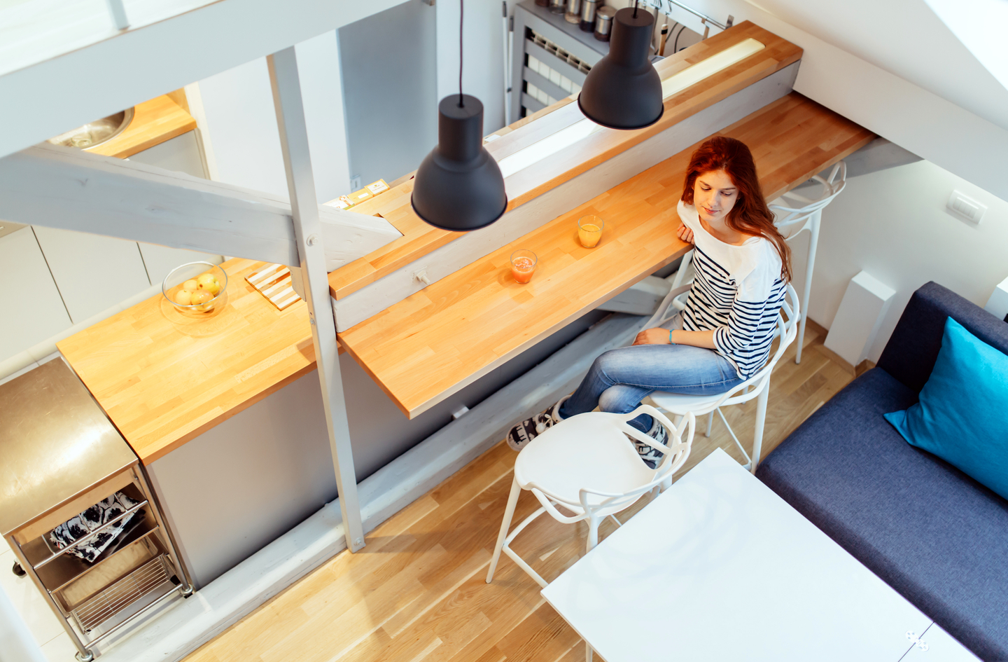 A well-organized small kitchen with light wood cabinetry and extensive pull-out storage solutions throughout a compact U-shaped layout