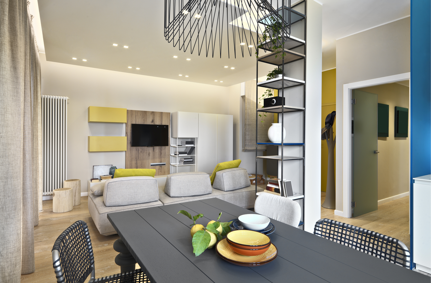 Tall industrial metal shelving unit used as vertical storage in a compact living and dining space