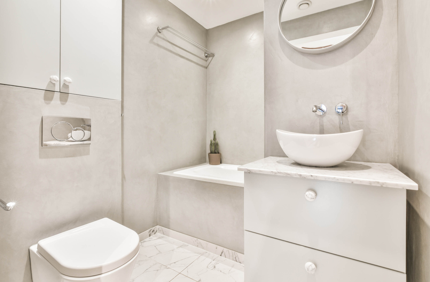 A wooden recessed shelf built into the wall above a toilet in a modern white bathroom with marble tile and white fixtures