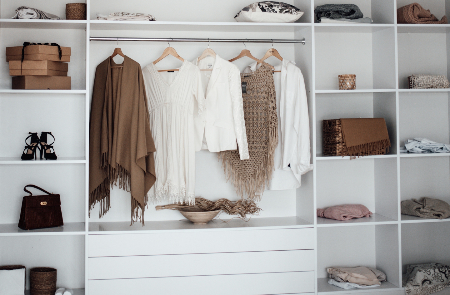 Small closet redesign example: two wire shelves organized with neatly folded items and storage containers inside a reach-in closet